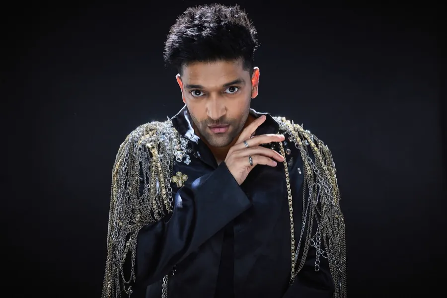 Guru Randhawa in a black fringe jacket, hand at his chin