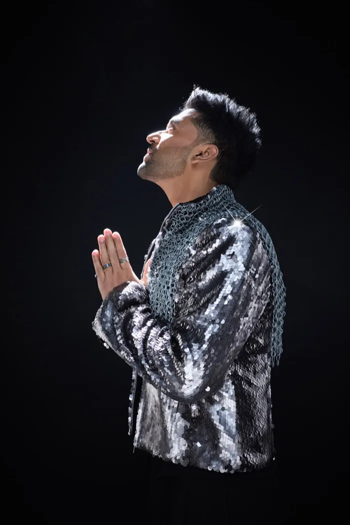Guru Randhawa, eyes closed, hands pressed together in prayer